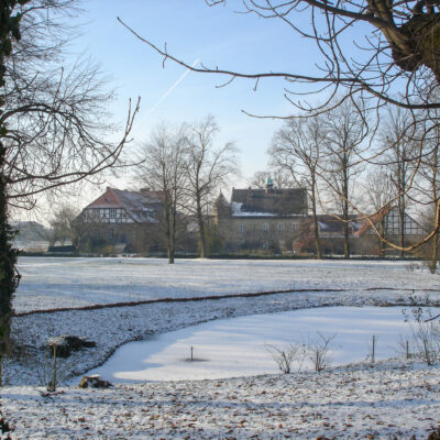 Winterlicher Lustgarrten, zugefrorener Teich mit Herrenhaus und Schloss im Hintergrund