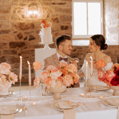 Hochzeitsshooting im Torhaus RIttergut Remeringhausen - Brautpaar am Tisch, Rosendeko im Vordergrund, Torte im Hintergrund